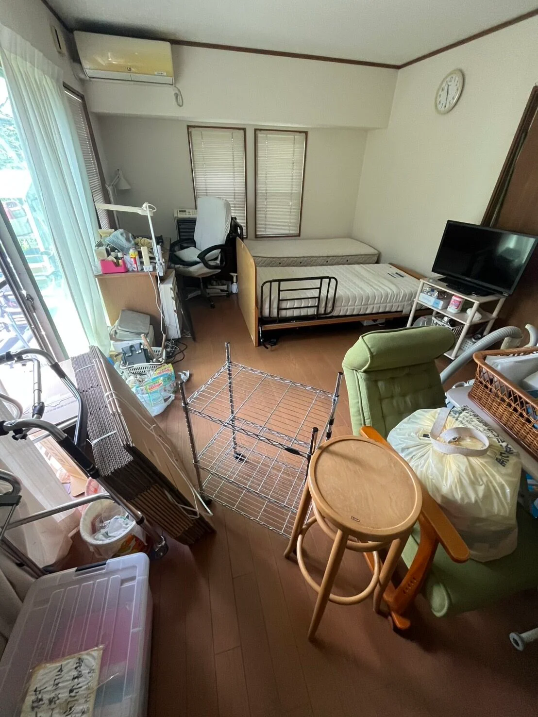 片付け前：ベッドや家具、ごみ袋などが置かれた部屋