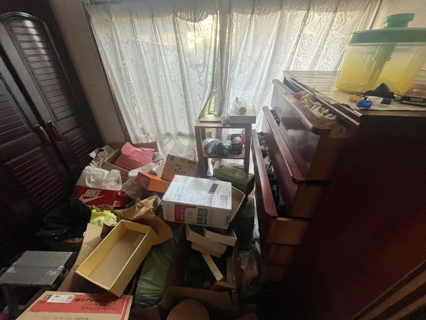 片付け前：段ボール箱や荷物、衣類が散乱した部屋