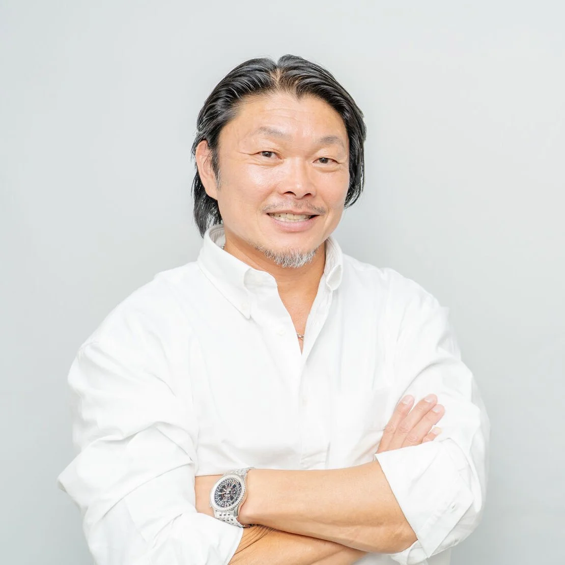 白いシャツを着て腕を組み、笑顔で立つ代表者